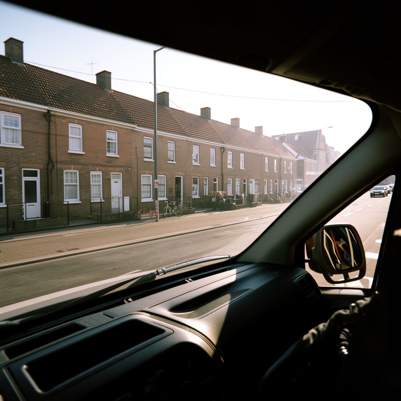 Street with terraced houses, seen through the windscreen of the work van